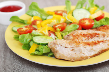 Grilled chicken breast with raw vegetables salad	