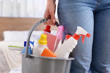 Woman with set of cleaning supplies in flat