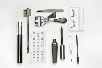 Mascara with false eyelashes and tools on white background