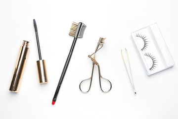 Mascara with false eyelashes and tools on white background