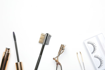 Mascara with false eyelashes and tools on white background