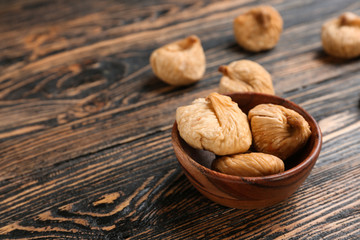 Bowl with tasty dried figs on wooden background