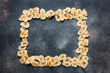 Frame made of tasty dried banana on grey background