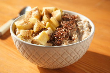 Bowl with tasty sweet oatmeal on wooden table