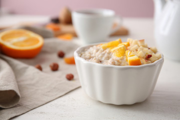 Bowl with tasty sweet oatmeal on white wooden table