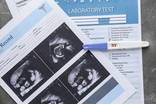 Sonogram image and pregnancy test on grey background