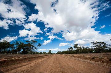 Fototapeta na wymiar Long straight red dirt road in Australia's outback.
