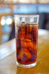 glass of black cola soft drink on wooden table