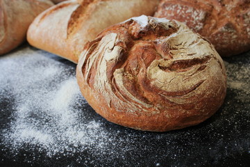 Assortment of fresh bread on black background. Freshly baked homemade bread loaf on rustic dark...
