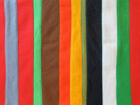 coverlet made of long strips of felt  in different colors sewn together