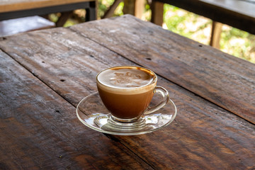 a cup of hot coffee in a glass coffee cup on old wood table