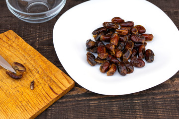 Hushaf - date milk, a traditional dish of Ramadan, cooking, ingredients, cut pitted dates, a knife and a date stone lie on a cutting board, there is a plate with dates next to it