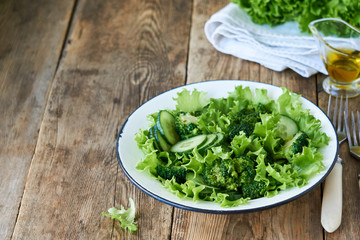 Vegetable salad with broccoli, cucumbers and lettuce in a white bowl 