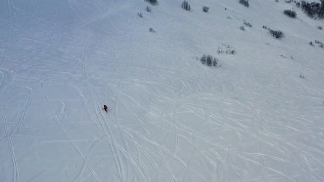 Aerial footage of a man freeriding down the hill on the fresh powder snow, 4k