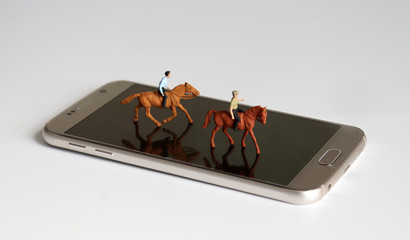 Two miniature horses with riders on a smartphone.