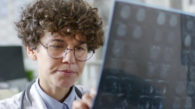 Close up of female Caucasian doctor face looking at x-ray image and analyzing it