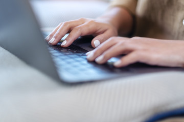 Closeup image of woman's hands using and typing on laptop keyboard