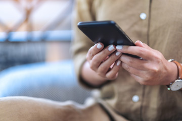 Closeup image of a woman's hands holding and using mobile phone