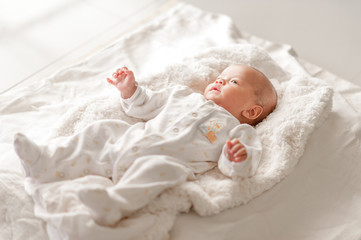 Fototapeta na wymiar Cute baby boy in a white light bedroom Newborn baby is cute. In bedding for children born - images