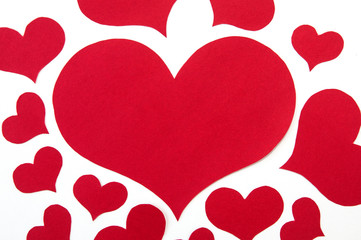 red hearts of different sizes cut from red paper on white background