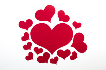 red hearts of different sizes cut from red paper on white background