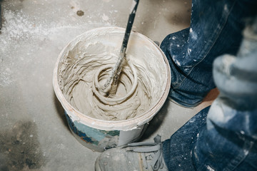 Man is mixing putty in the bucket Grind of wall. Maintenance repair works renovation in the flat....