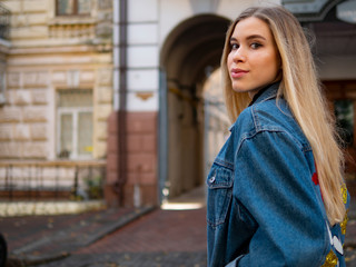 attractive girl with flowing hair in a denim jacket against the background of an old building