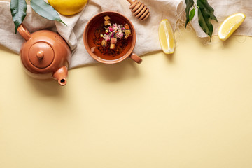 Tea concept, top border or frame of teapot and teacup surrounded with green tea leaves and lemon, view from above