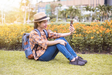 Naklejka na ściany i meble Asian women tourists are taking and selfie photos with a smartphone at flowers garden. traveling in the holidays.