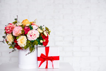 bouquet of beautiful summer flowers and gift box over white wall background with copy space