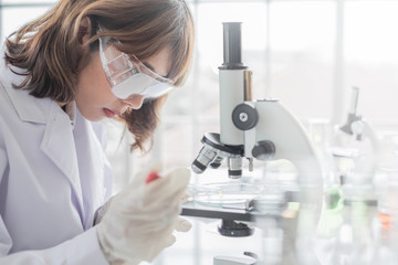 A young Asian woman scientist working in laboratory with test tube microscope and solutions.