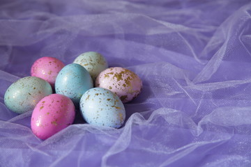 Colorful Easter eggs in purple fabric in the shape of a flower with copy space for text. Easter background.