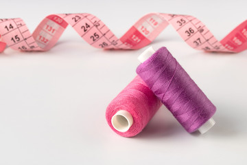 Sewing accessories for needlework in pink and purple tones on white background