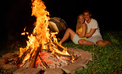 CLOSE UP: Beautiful girl cuddling with her boyfriend by the warm campfire.