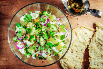 new potato cucumbers, boiled egg and greens salad in a glass cup on a wooden table with rice and buckwheat flat cake