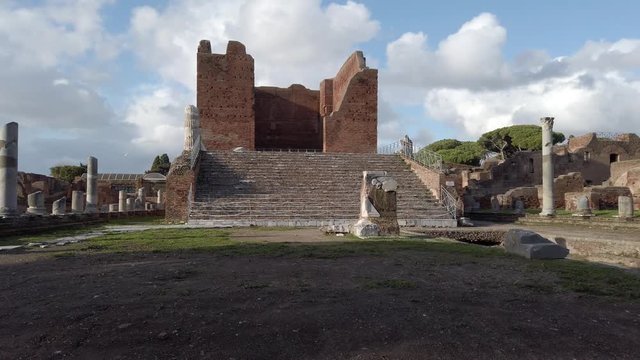 Panorama at archaeological excavations of Ostia Antica with the Capitolium  surrounded by ruins, columns and remains of statues and bas-reliefs