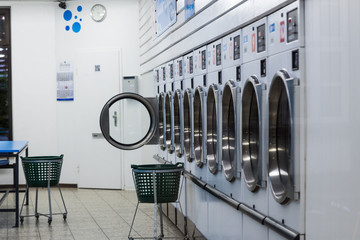 metallic laundry machines standing in a row and laundry baskets