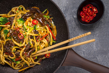 Udon Stir-Fry Noodles with Beef and Vegetables in Wok Pan on Dark Background