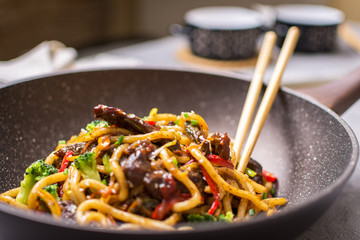 Udon Stir-Fry Noodles with Beef and Vegetables in Wok Pan on Dark Background
