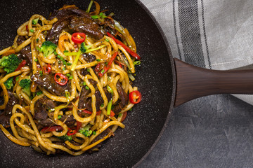 Udon Stir-Fry Noodles with Beef and Vegetables in Wok Pan on Dark Background