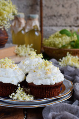 Chocolate capcakes with vanilla cream sprinkled with white chocolate and elderberry flowers. Vintage style. Copy space.