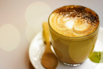 Hot latte coffee on the table with blurred bokeh background.