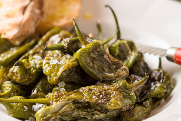 Green Padron Peppers with Crisp Bread in Rustic White Plate. Pimientos de Padrón.