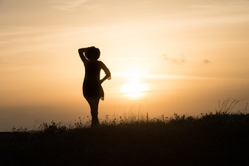 Woman with hat silhouette at sunset