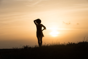 Woman with hat silhouette at sunset