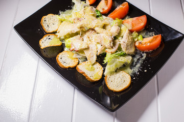 Caesar salad with bacon and quail eggs Black plate