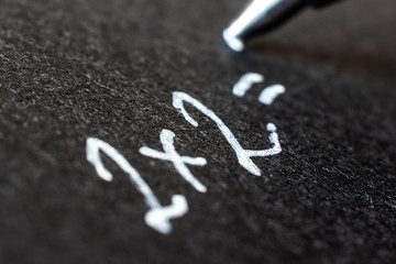 Fototapeta premium Handwritten white lettering on black paper, photographed close-up. Macro photo suitable for background.