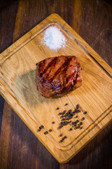 Beef steak on wood board with fork and knife herbs spices and salt