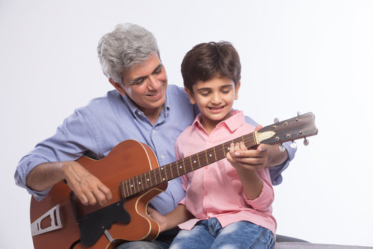 Grandfather and grandson playing guitar	