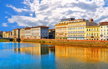 waterfront and riverscape with  colorful reflections and old historical buildings and brigde on Arno river and cloudy blue sky in background in old part of Florence